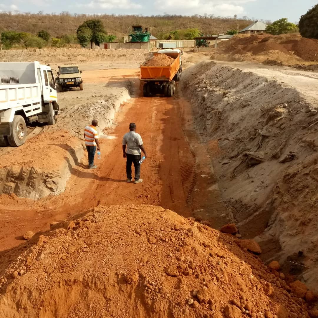 Team walking the TSF haul road between dump trucks