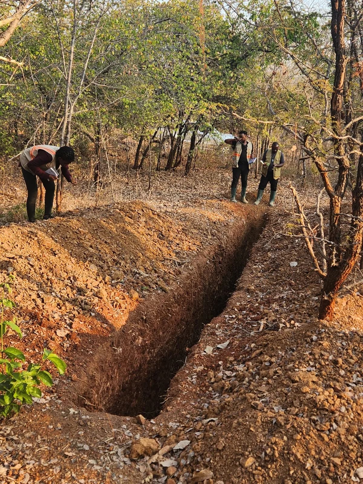 Team sampling and recording data along an exploration trench