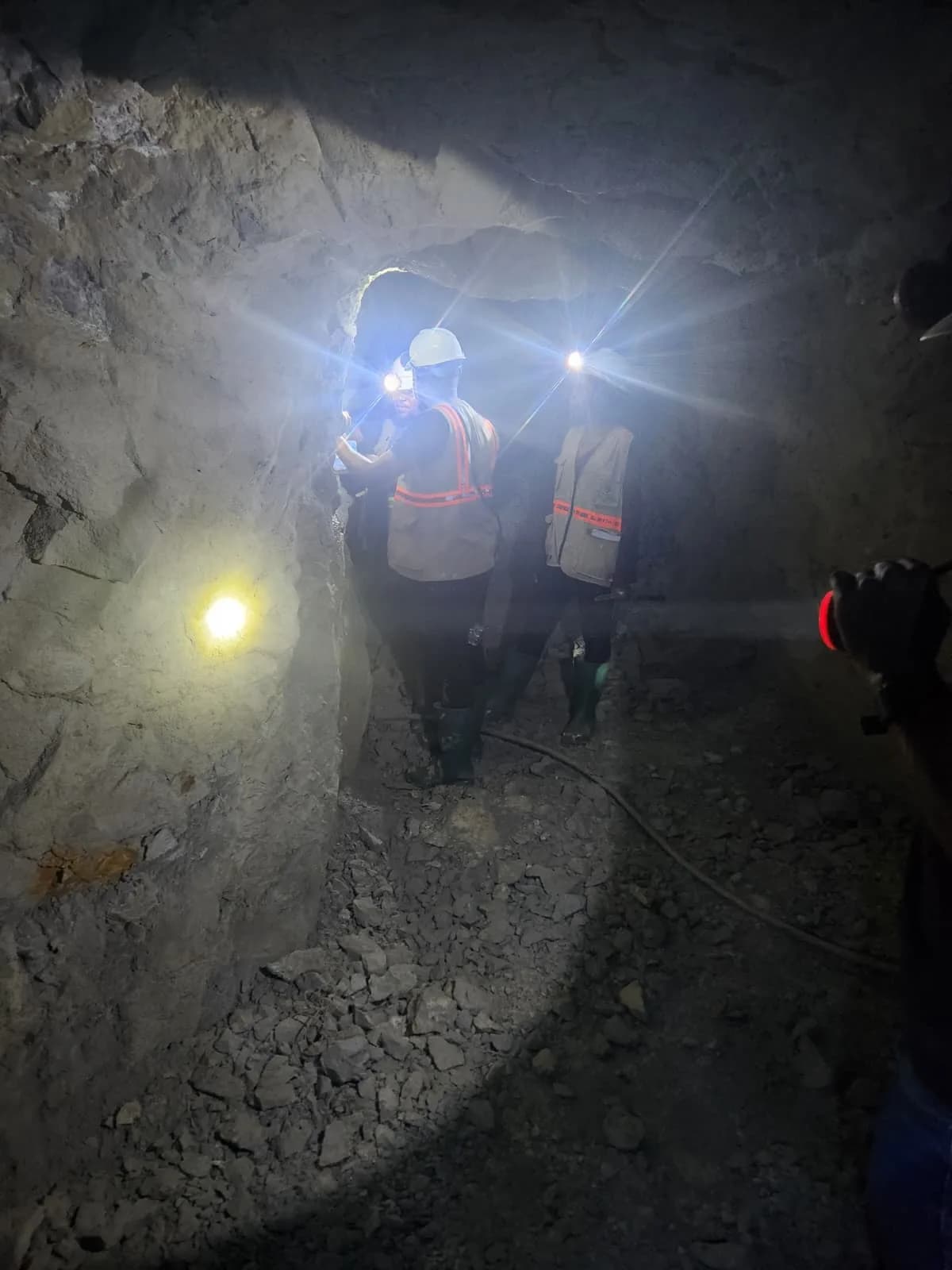 Geologists walking through an underground exploration tunnel