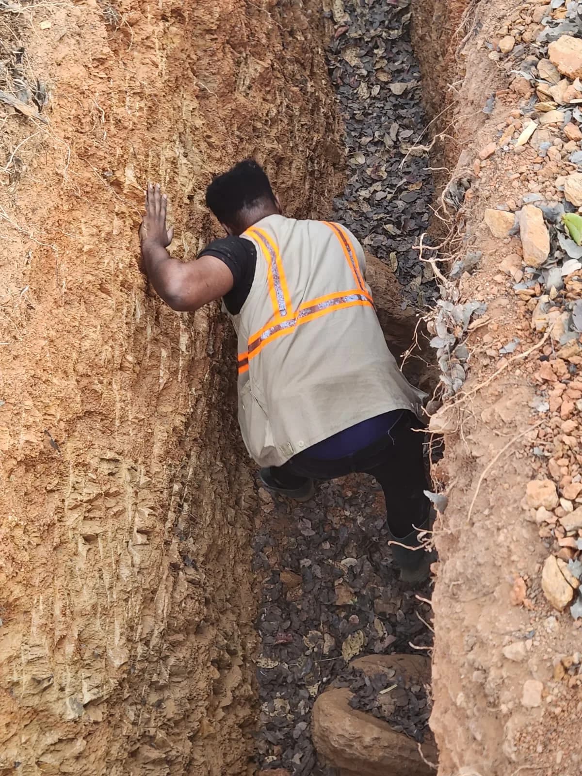 Geologist examining the soil profile in an exploration trench