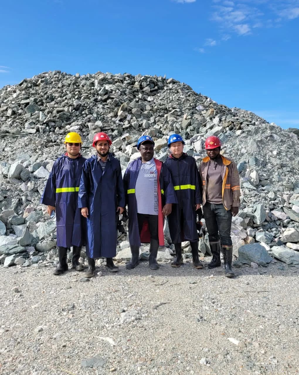 Team beside crushed ore at a Gengetatu Extech mining site